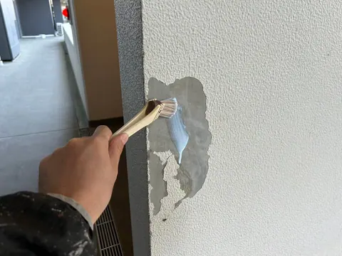 欠損部分へ補修材を塗り込んでいる作業中の外壁