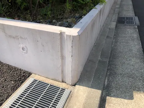 角に縦方向のひび割れが見られる塀の補修前